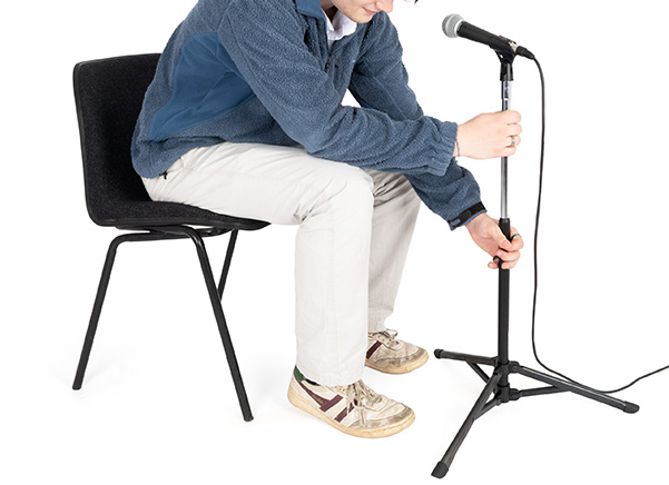 Seated man adjusting microphone stand