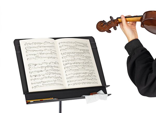 Violin player next to Orchestral music stand with pencils and rosin on the extra storage lip